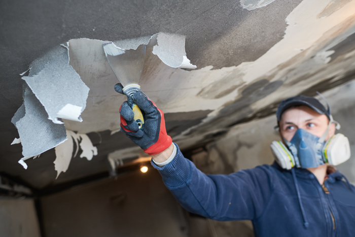 Man in blue shirt and gloves painting ceiling - Disaster clean-up and restoration services