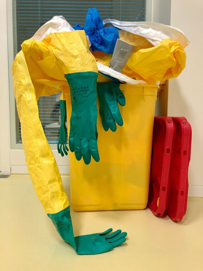 A yellow trash can with gloves on top, symbolizing waste disposal and cleanliness.


