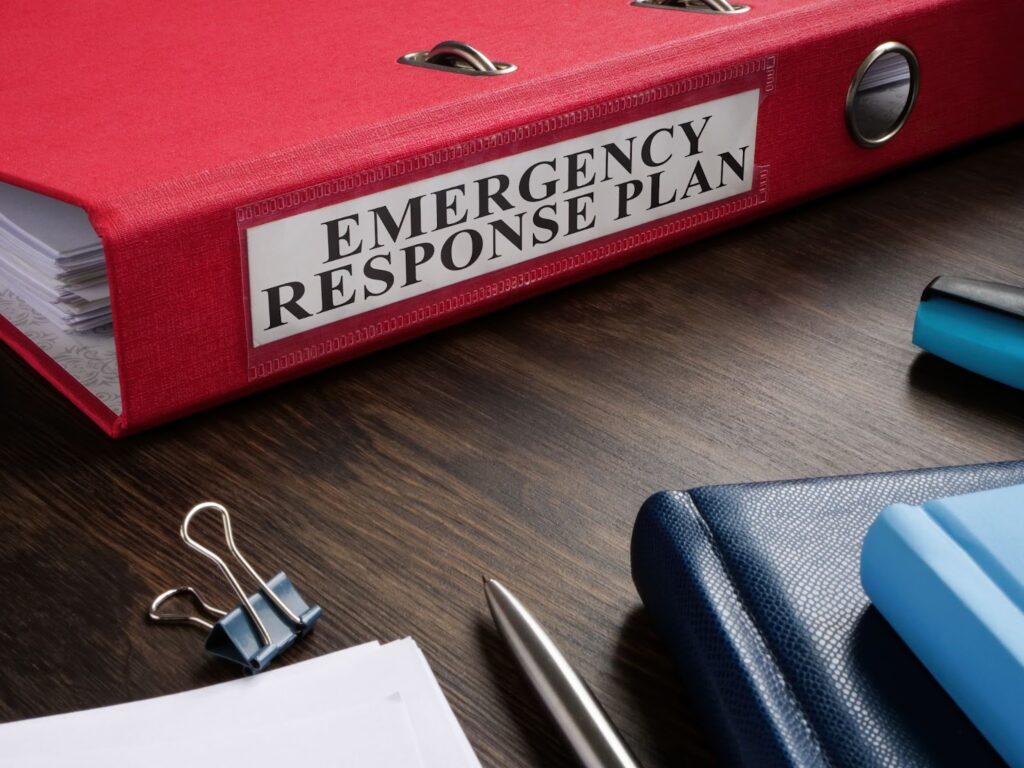 Emergency response plan on desk with notebook, pen, and binder for family emergency plan and disaster preparedness
