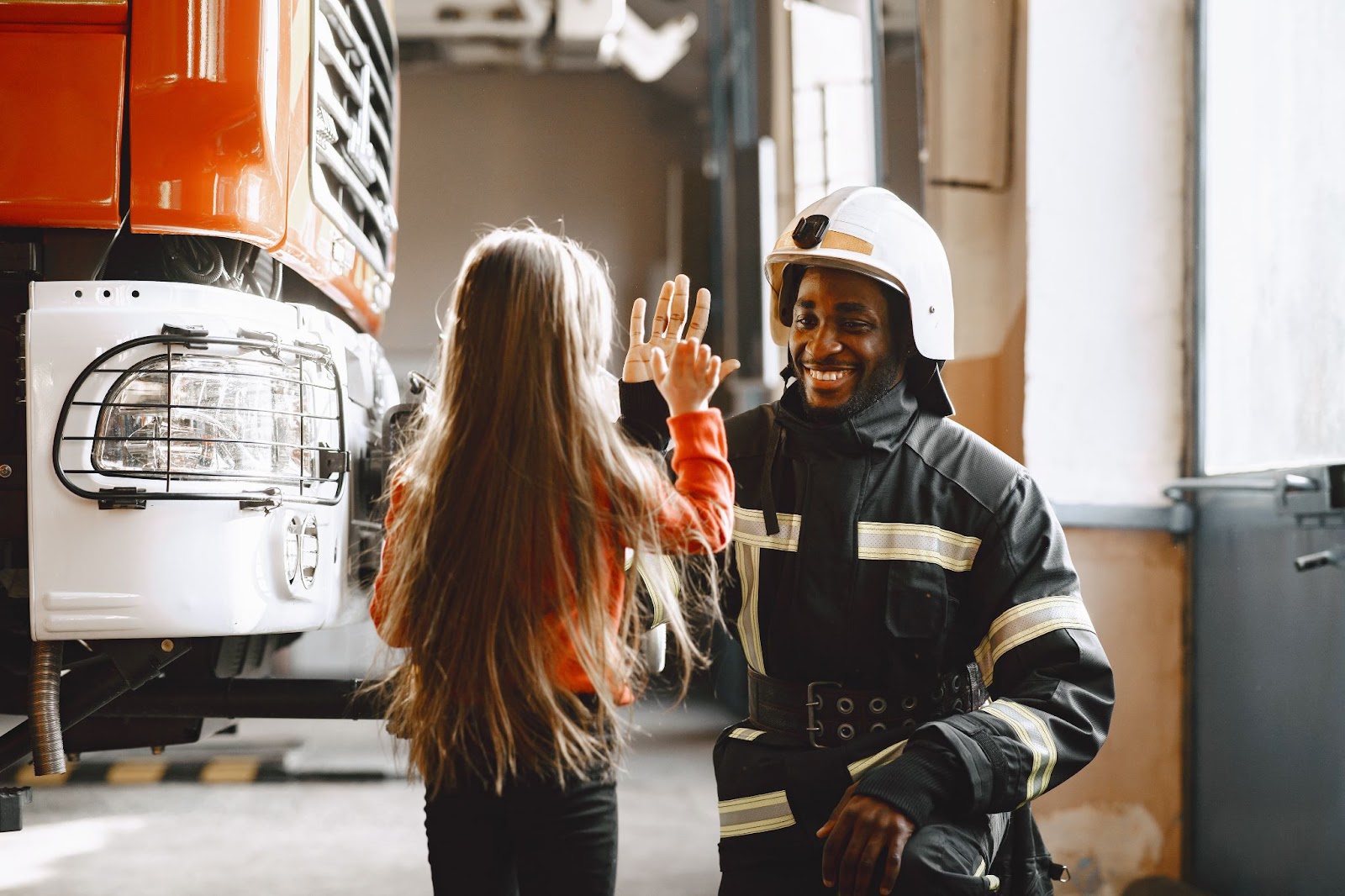 A young girl and a firefighter in a warehouse, emphasizing fire safety measures.

