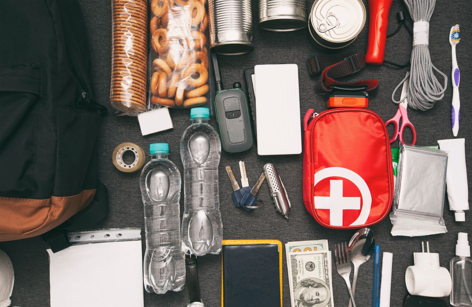 A disaster preparedness kit on a table backpack, water bottle, and other essential items for preparing for a disaster.