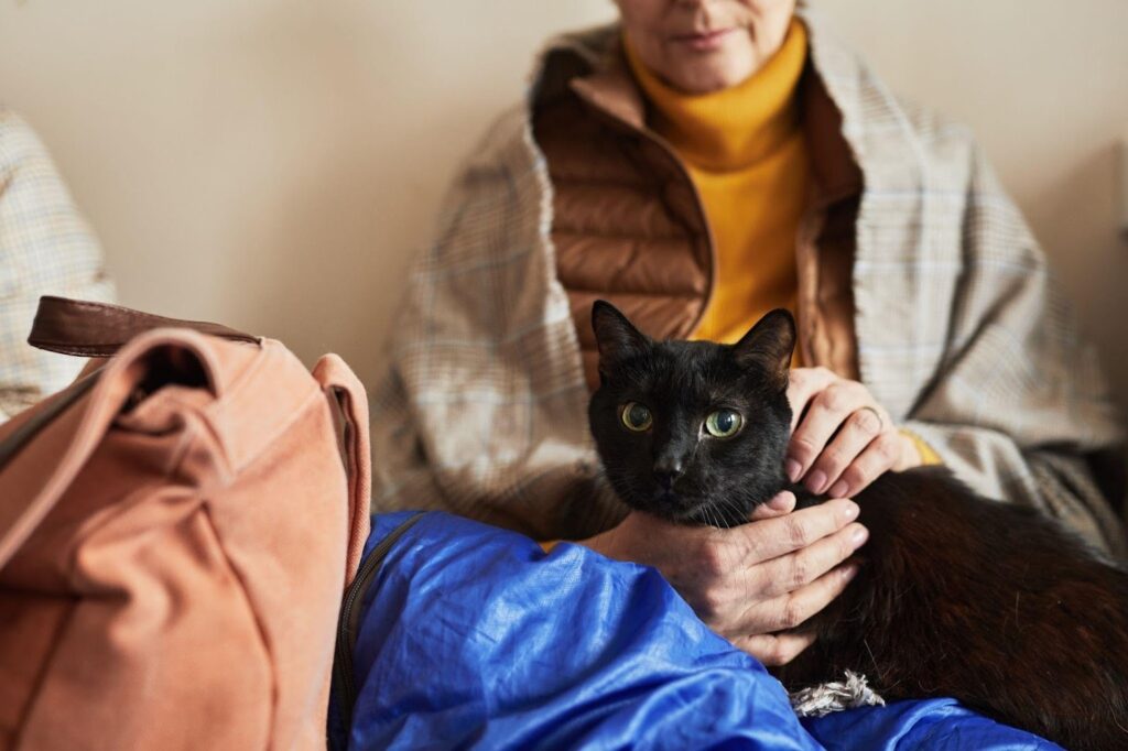 Mature woman smiling while cuddling a black cat in her arms