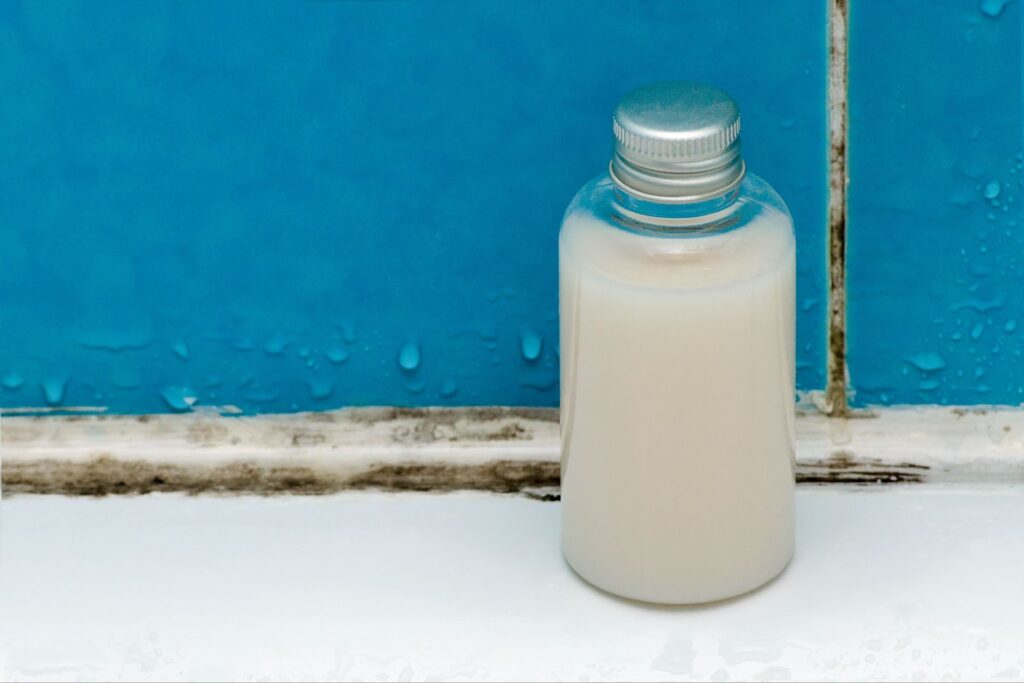 A bottle of liquid soap placed on a clean white tile surface, emphasizing hygiene in a mold-free environment.