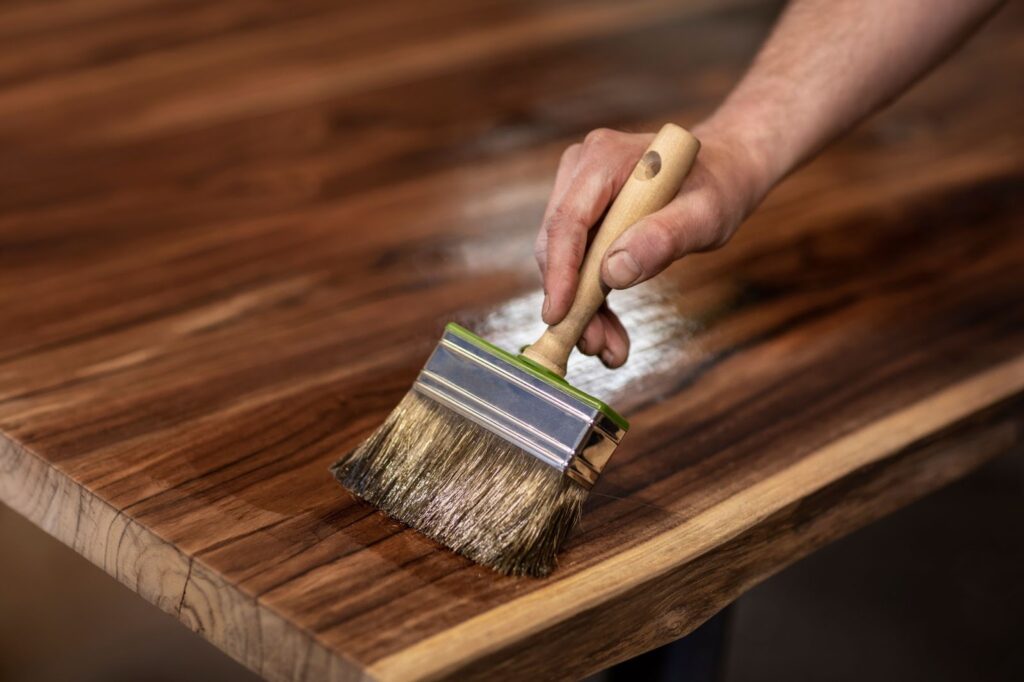 A person carefully brushes a water-damaged wooden table, working to restore its original beauty and finish.