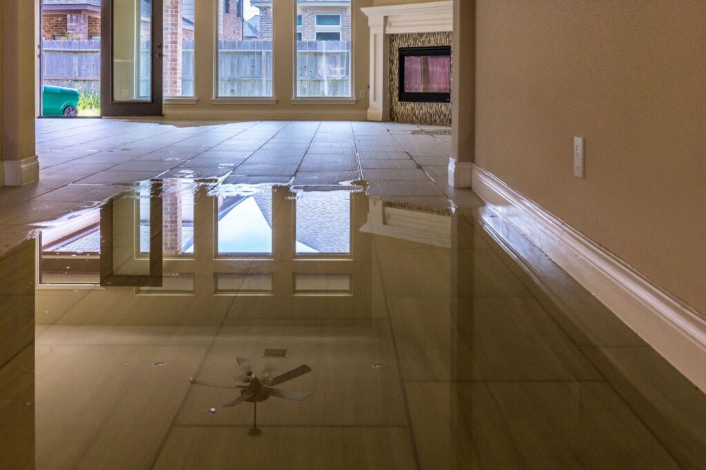 A flooded home interior with water covering the floor and a ceiling fan, highlighting the need for professional disaster cleanup.