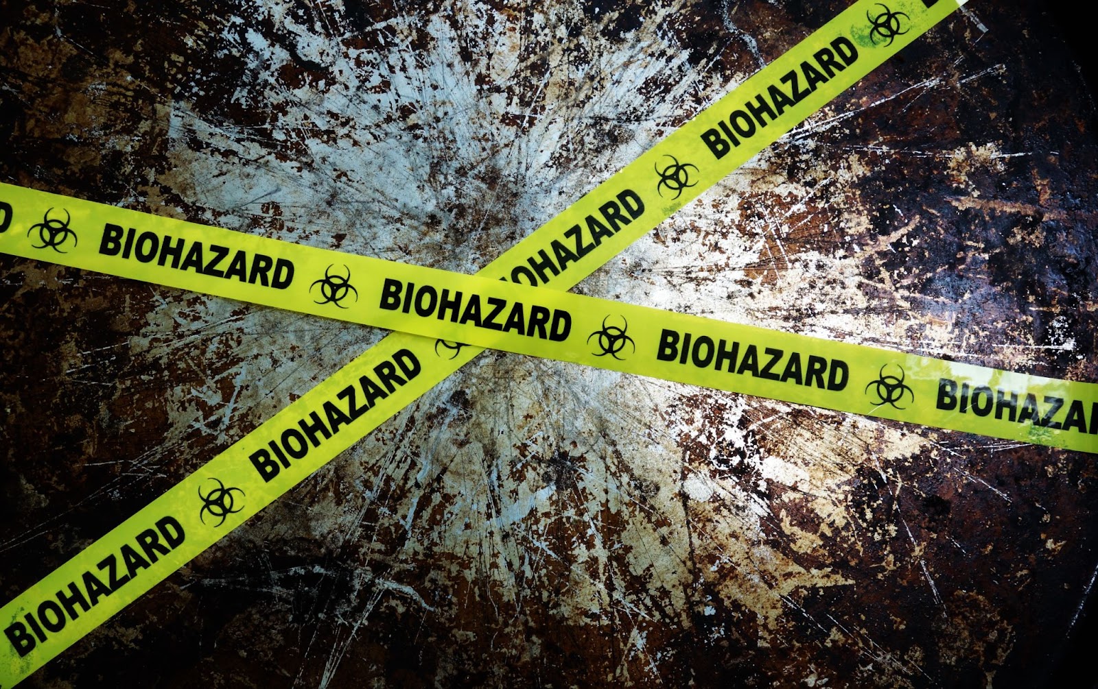 Yellow and black biohazard tape placed on a table, indicating a biohazard cleaning area for safety and caution.